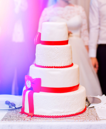 White wedding cake with red ribbonsの写真素材