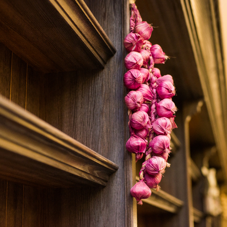 Bunches of yellow onions hanging and drying outside a rustic window.の写真素材