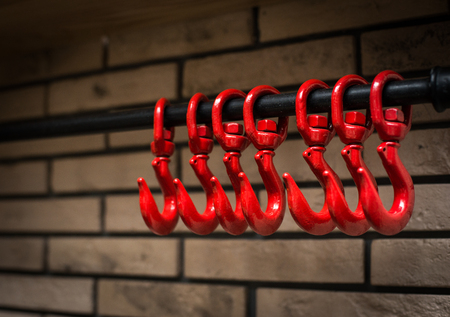 Decorative hanger in the form of red hooks on a brick wall. Decor in a cafeの写真素材