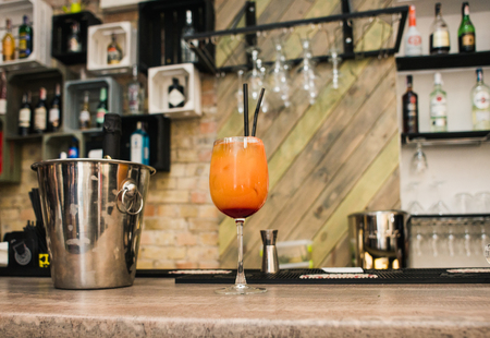 Glass of orange cocktail with a straw on the background of a bar counter.の写真素材
