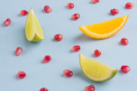 fresh pieces of lime, orange, pomegranate on a blue backgroundの写真素材