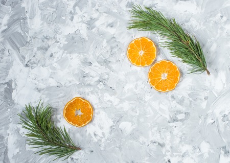 Christmas decorations. A branch of a Christmas tree and an orange slice on a light concrete background. View from above.の写真素材