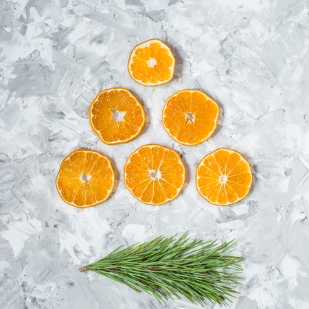 Christmas decorations. A branch of a Christmas tree and an orange slice on a light concrete background. View from above.の写真素材