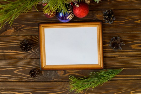 Brown wooden background with a festive Christmas decoration, fir tree, garlands, pine cones, frame...