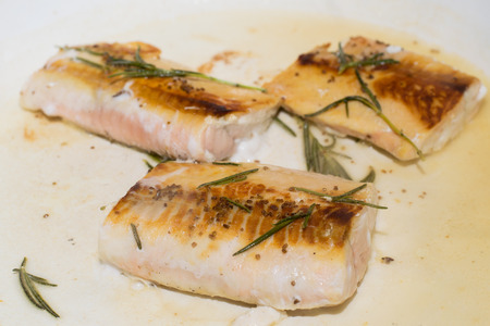 Salmon fillets getting cooked on a pan with rosemaryの写真素材