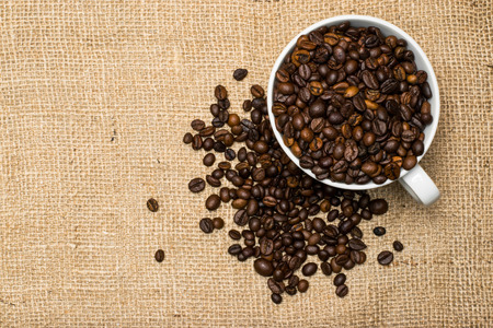 Cup full of coffee beans over cloth backgroundの写真素材