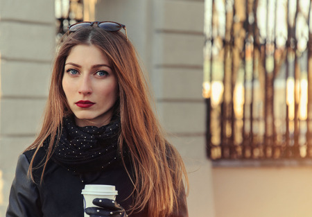 beautiful serious young businesswoman with coffee on the streetの写真素材
