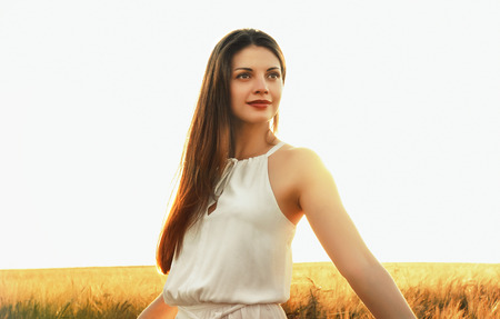 attractive young woman enjoy beautiful nature at the sunset background in the fieldの写真素材