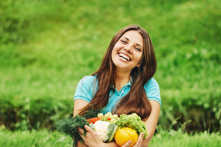 cute happy woman with organic healthy fruits and vegetables outdoorsの写真素材