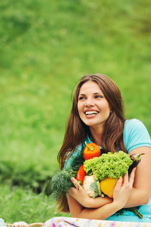 cute happy woman with organic healthy fruits and vegetables on the picnic in the park outdoorsの写真素材
