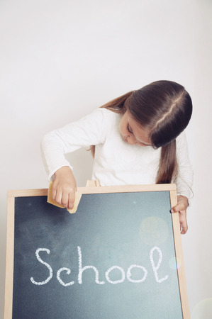 cute lovely school girl holding chalkboard in studio, education conceptの写真素材