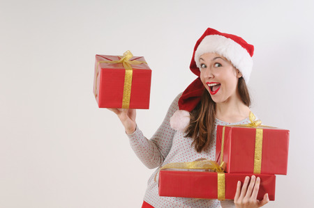 beautiful young woman in santa hat with present boxes for Christmas or New Year holiday on white...