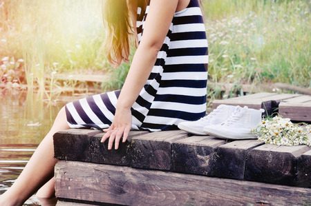 girl sitting on the pier at the lake in sunny hot summer day outdoor, vacation conceptの写真素材
