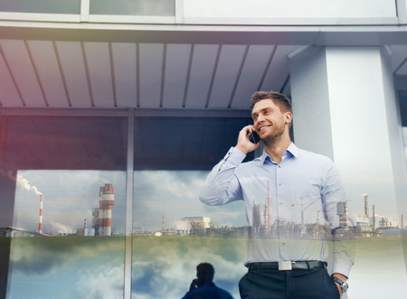double exposure of businessman with phone device and industrial enterprise on urban building backgroundの写真素材