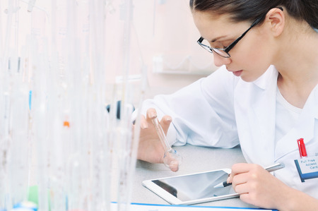 chemical laboratory scene: attractive young student scientist observing liquid measures medicine conceptの写真素材