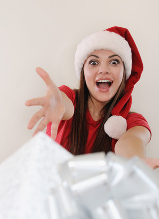 happy emotional screaming woman in santa hat giving you a present box.の写真素材