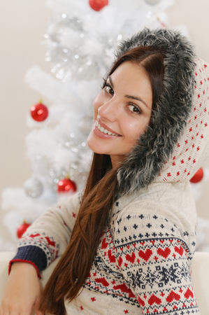attractive happy smiling young woman at home on Christmas tree background.の写真素材