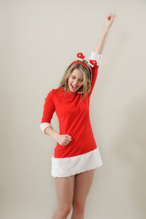 beautiful sexy girl wearing santa claus clothes show succes gesture; xmas concept; studio shoot over greyの写真素材