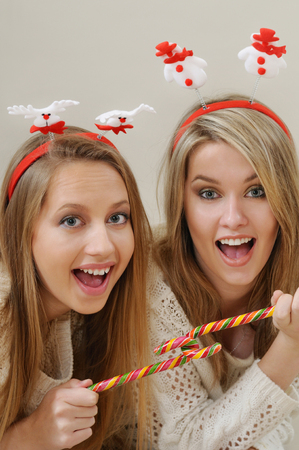 two beautiful young girls enjoying and having fun with Christmas sweet candys, happy holiday conceptの写真素材