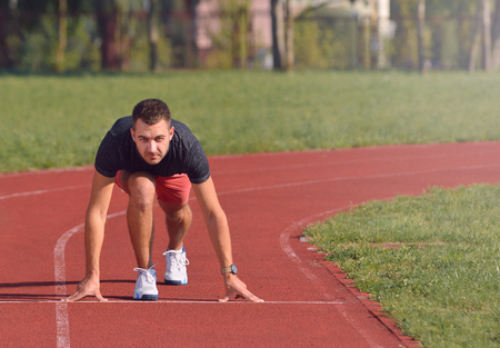 Athletic man on track starting to run. Healthy fitness concept with active lifestyle.の写真素材