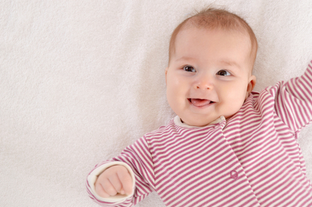 Happy newborn girl lying on her back and smile. Happy motherhood conceptの写真素材