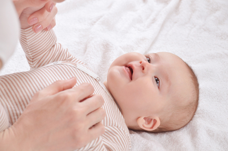 Happy mother play with hands of the newborn baby. Cute newborn girl happy smiling. Happy motherhood conceptの写真素材