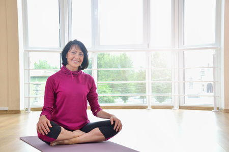 Mature woman sitting on the floor in lotus positionの写真素材