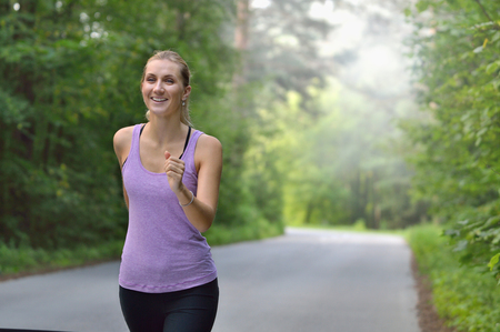 Female runner jogging during outdoor workout in a park.の写真素材