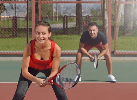 Couple playing doubles at the tennis court. Waiting for second serve.の写真素材