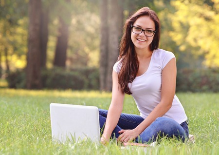 Student girl sitting on the grass in the parkの写真素材