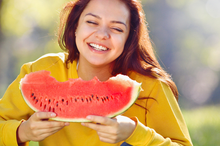 Happy young woman eating watermelon in the park and smile.の写真素材