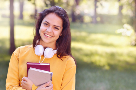 Young beautiful and trendy student girl holding books. Casual teenage girl preparing to schoolの写真素材
