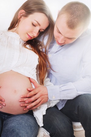 happy pregnant woman with her husband touching her belly with hands. Happy family conceptの写真素材