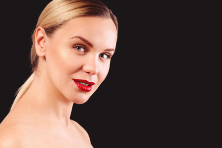 Young adult woman with makeup and a fashionable hairstyle poses in studio on black background. Close up female faceの写真素材