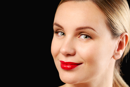 Young adult woman with makeup and a fashionable hairstyle poses in studio on black background. Close up female faceの写真素材