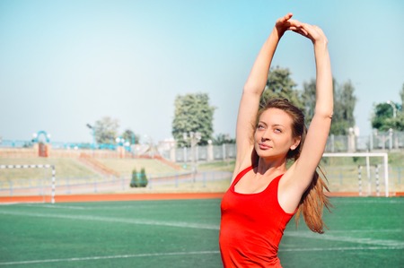 Beautiful and athletic girl with clothes for jogging standing with her hands behind her head and looking at the camera. Beautiful smiling young athlete woman working out. Fitness conceptの写真素材