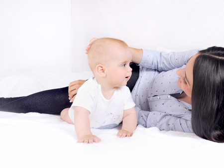 Young mother with baby at home. Mom nursing baby. Woman and new born boy relax in a white bedroomの写真素材