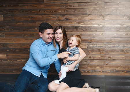 Happy proud young father having fun with little daughter on mother hands. Family spending time at home with their daughter. Happy parenthood conceptの写真素材