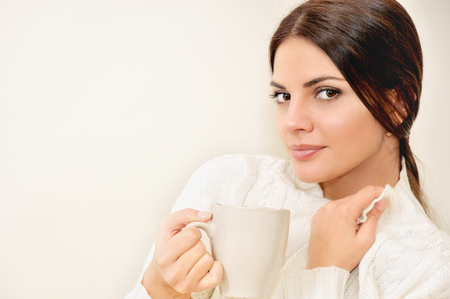 Beautiful young woman enjoying a cup of coffee while relaxing at home.の写真素材