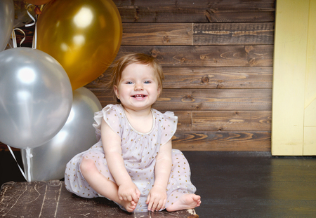 Happy little girl celebrate her first birthday party with balloons. Happy birthday baby. Childhood, holidays and travel conceptの写真素材