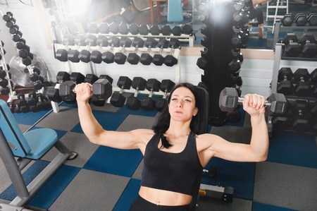 Young athletic woman training hard with dumbells at gym. Fitness and healthy lifestyle conceptの写真素材