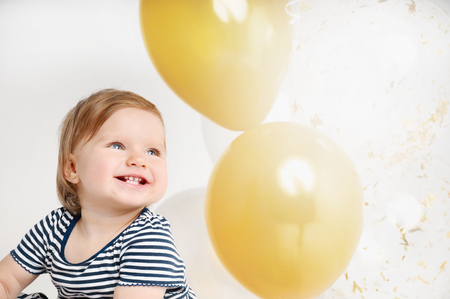 Happy and smiling one year old baby portrait with balloon background. Cute infant with group of ballsの写真素材