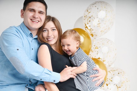 Young family of three people, mom's dad and daughter's one year old stands inside the room. Happy parenthood conceptの写真素材