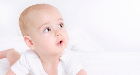 Happy child lie on white bed and smile. Happy childhood concept. Close up portraitの写真素材