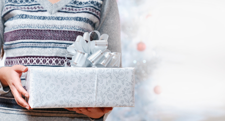 Close up picture of woman in grey sweater holding gift box over white. Merry Christmas and Happy New Year conceptの写真素材