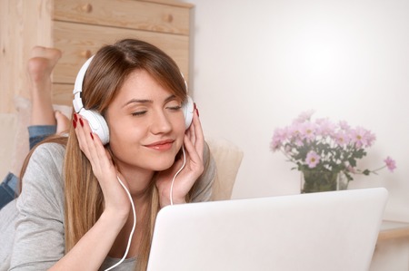 Attractive woman listening music on the sofa. Beautiful girl listening to music while resting on sofa at home. Happy people and leisure conceptの写真素材