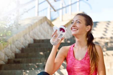 Sporty woman drinking water after jogging. Fitness and healthy lifestyle conceptの写真素材