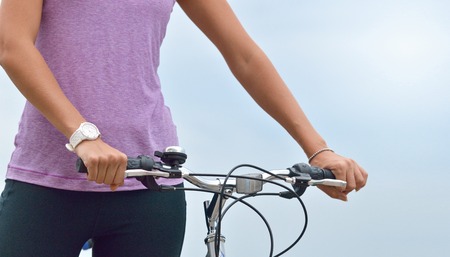 Close up young woman hand on the bicycle handlebars. Beautiful sporty girl hand griping bicycle handle. Active lifestyle conceptの写真素材