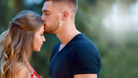 A couple in love beautiful young men kissing in a summer park on a sunny day. Sincere emotions and love on the planetの写真素材