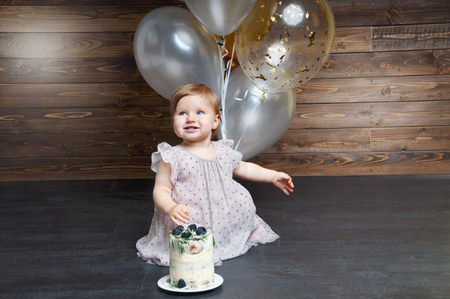 Beautiful little girl celebrating birthday party with balloons and birtday cake. Family celebration of the child. One year party. Cute infant with group of ballsの写真素材